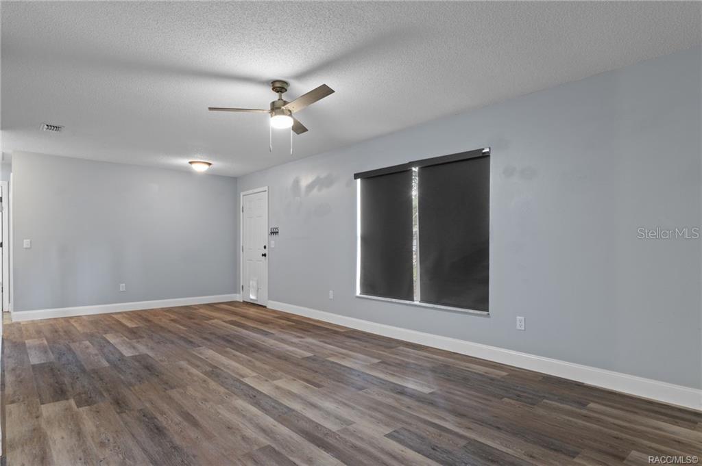 An empty room with light gray walls, wood-look flooring, a ceiling fan, and a window — 1317 CARL STREET, INVERNESS, FL