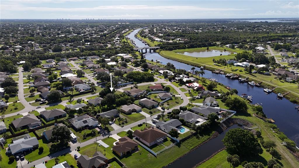 An aerial view shows a suburban neighborhood with houses, a canal, and a bridge — 2668 SW CAMEO BOULEVARD, PORT ST LUCIE, FL