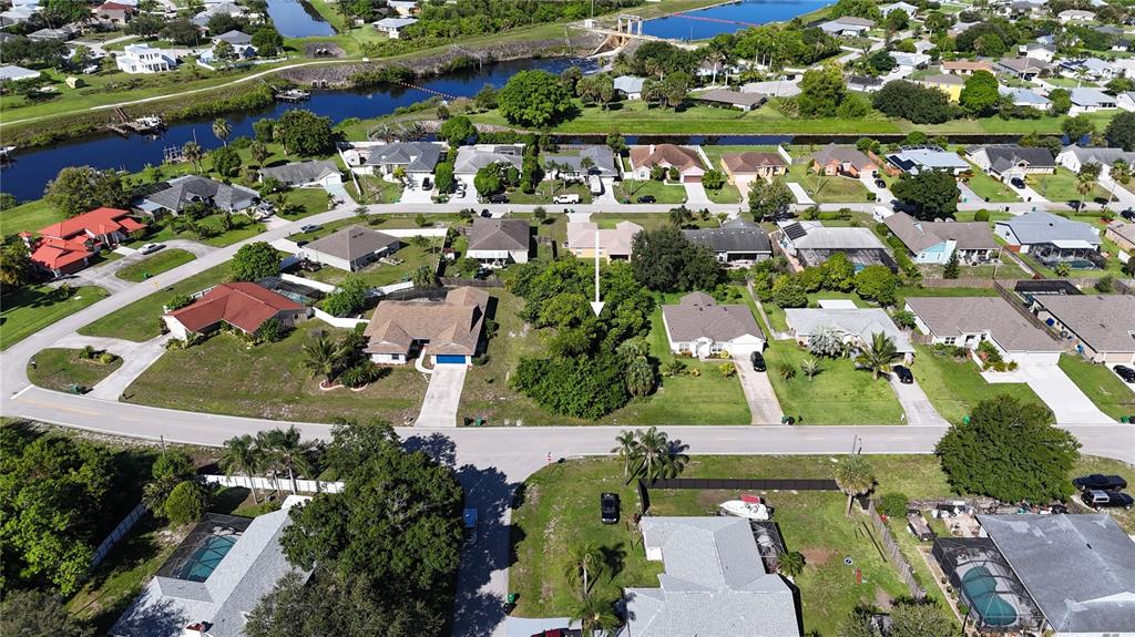 An aerial view shows a residential neighborhood with a vacant, tree-covered lot marked by an arrow — 2668 SW CAMEO BOULEVARD, PORT ST LUCIE, FL