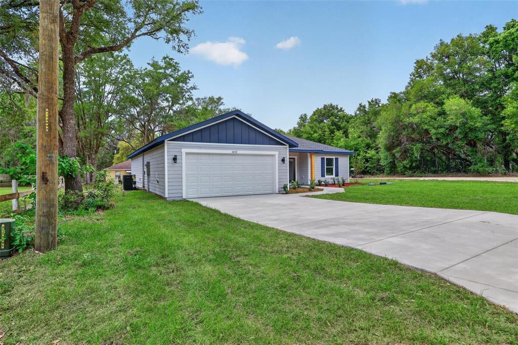 A single-story house with light gray siding, a blue gable roof, and a concrete driveway — 13761 SW 114TH PLACE, DUNNELLON, FL