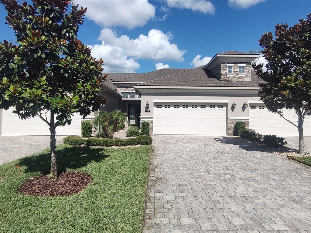 A single-story house with a three-car garage, stone accents, and a paved driveway — 727 ALDENHAM LANE, ORMOND BEACH, FL