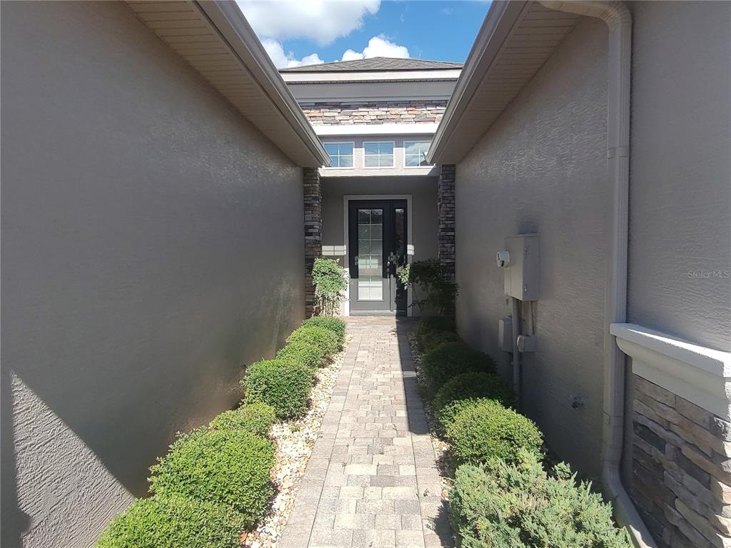 A stone paver walkway leads to a front door flanked by stone pillars and shrubs — 727 ALDENHAM LANE, ORMOND BEACH, FL