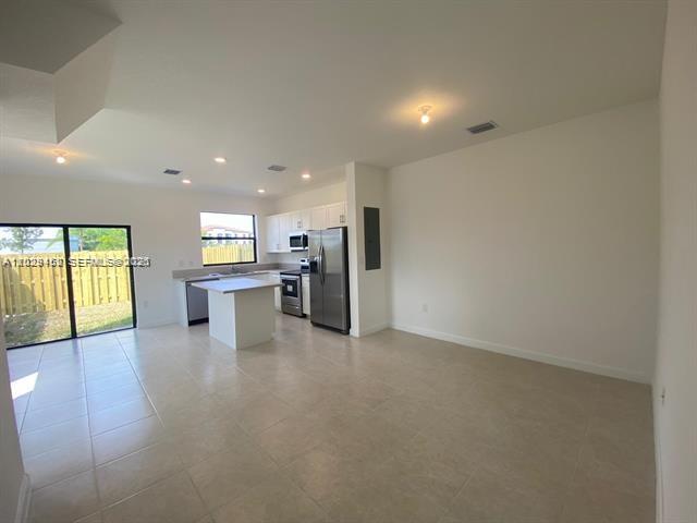 An open-concept kitchen with stainless steel appliances and a center island overlooks a living area — 593 NE 208th Ter, Miami FL 33179, MIAMI, FL