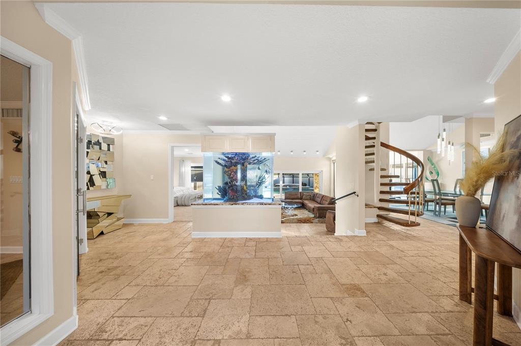 A spacious foyer features travertine tile floors, a large built-in aquarium, and a spiral staircase — 12416 STILLWATER TERRACE DRIVE, TAMPA, FL