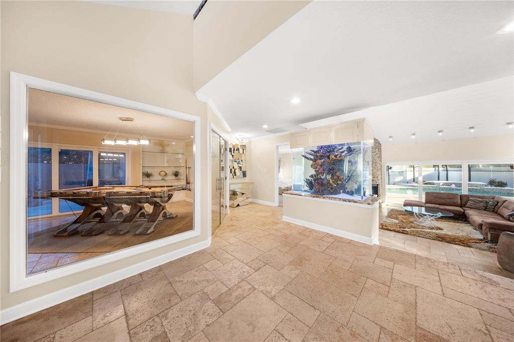 A tiled foyer features a large aquarium, a glass-walled game room, and a living area — 12416 STILLWATER TERRACE DRIVE, TAMPA, FL