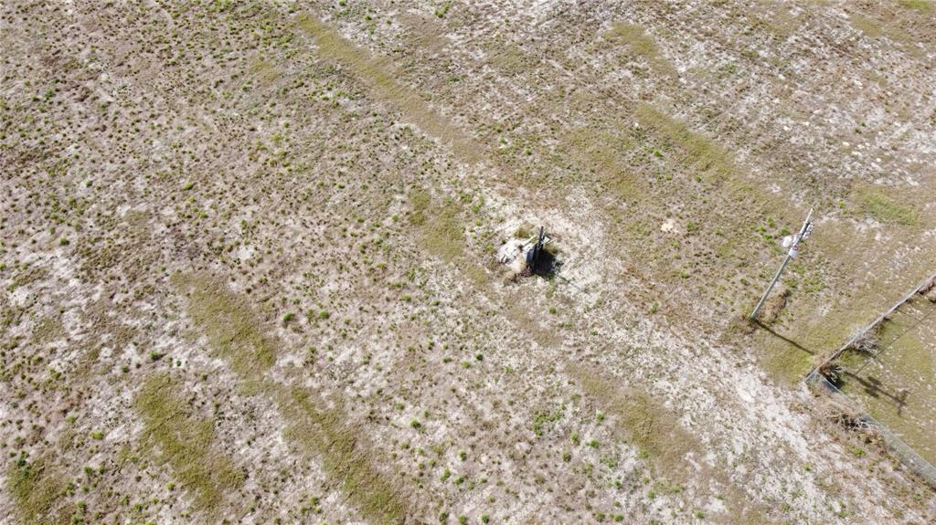 An aerial view of a vacant, grassy lot featuring a utility pole and small structure — 1/4 MOUNTAIN DRIVE, BABSON PARK, FL