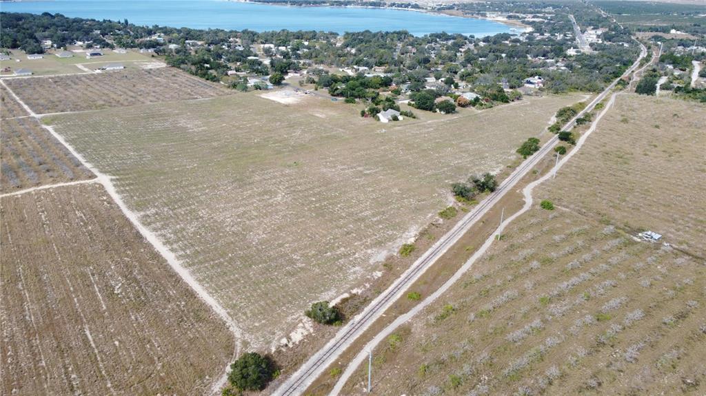 An aerial view shows a large, cleared rectangular plot of land bordering a railroad track — 1/4 MOUNTAIN DRIVE, BABSON PARK, FL