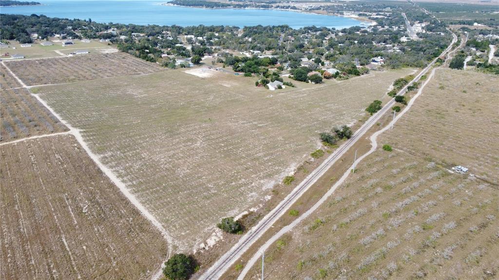 An aerial view shows a large, flat, undeveloped plot of land adjacent to railroad tracks — 1/4 MOUNTAIN DRIVE, BABSON PARK, FL