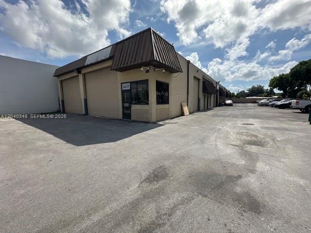 An exterior view of a commercial warehouse building with roll-up doors and a parking lot — 4237 NW 37 Ave # 4237, Miami FL 33142, MIAMI, FL