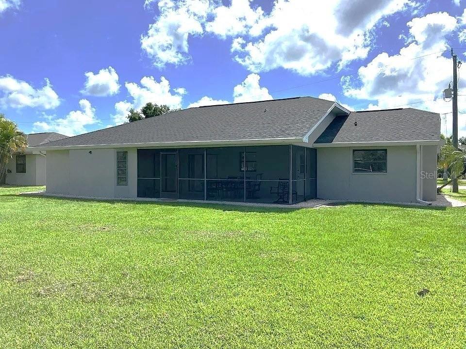 The rear exterior of a single-story house features a screened-in lanai and a large lawn — 367 MENDOZA STREET, PUNTA GORDA, FL