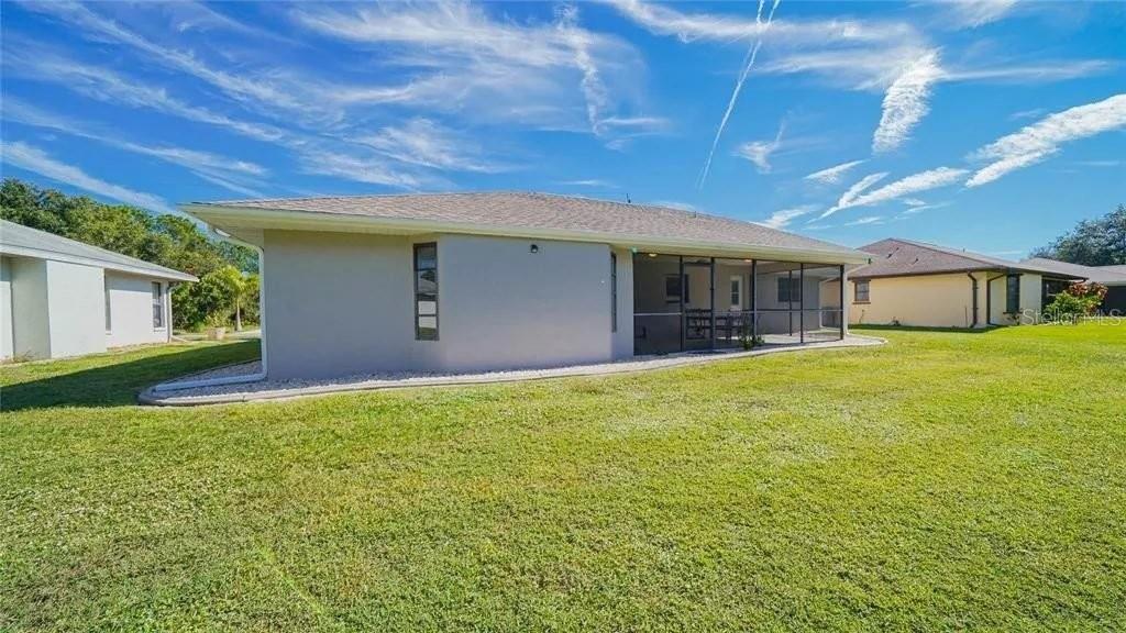 The exterior of a house features a screened-in back porch and a large grassy yard — 367 MENDOZA STREET, PUNTA GORDA, FL