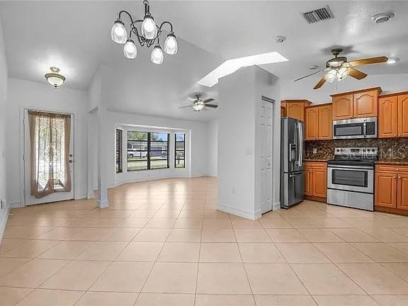 An open-concept kitchen and living area with tile flooring, wood cabinets, and a ceiling fan — 367 MENDOZA STREET, PUNTA GORDA, FL