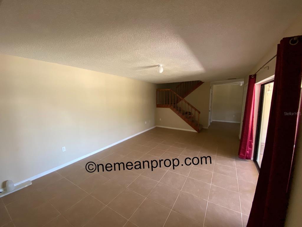 An interior view shows a living room with tile flooring and a wooden staircase — 2949 POPLAR AVENUE, LEESBURG, FL