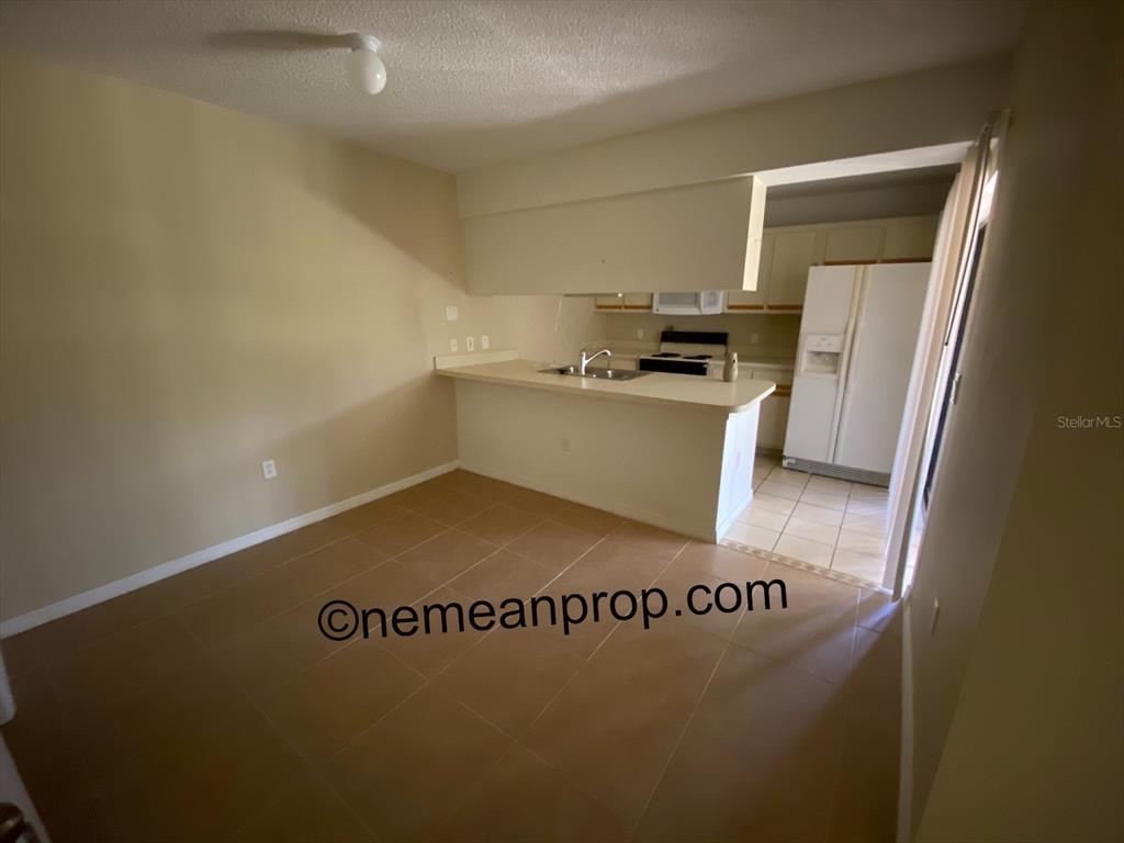 An open kitchen with a breakfast bar overlooks a tiled dining area — 2949 POPLAR AVENUE, LEESBURG, FL