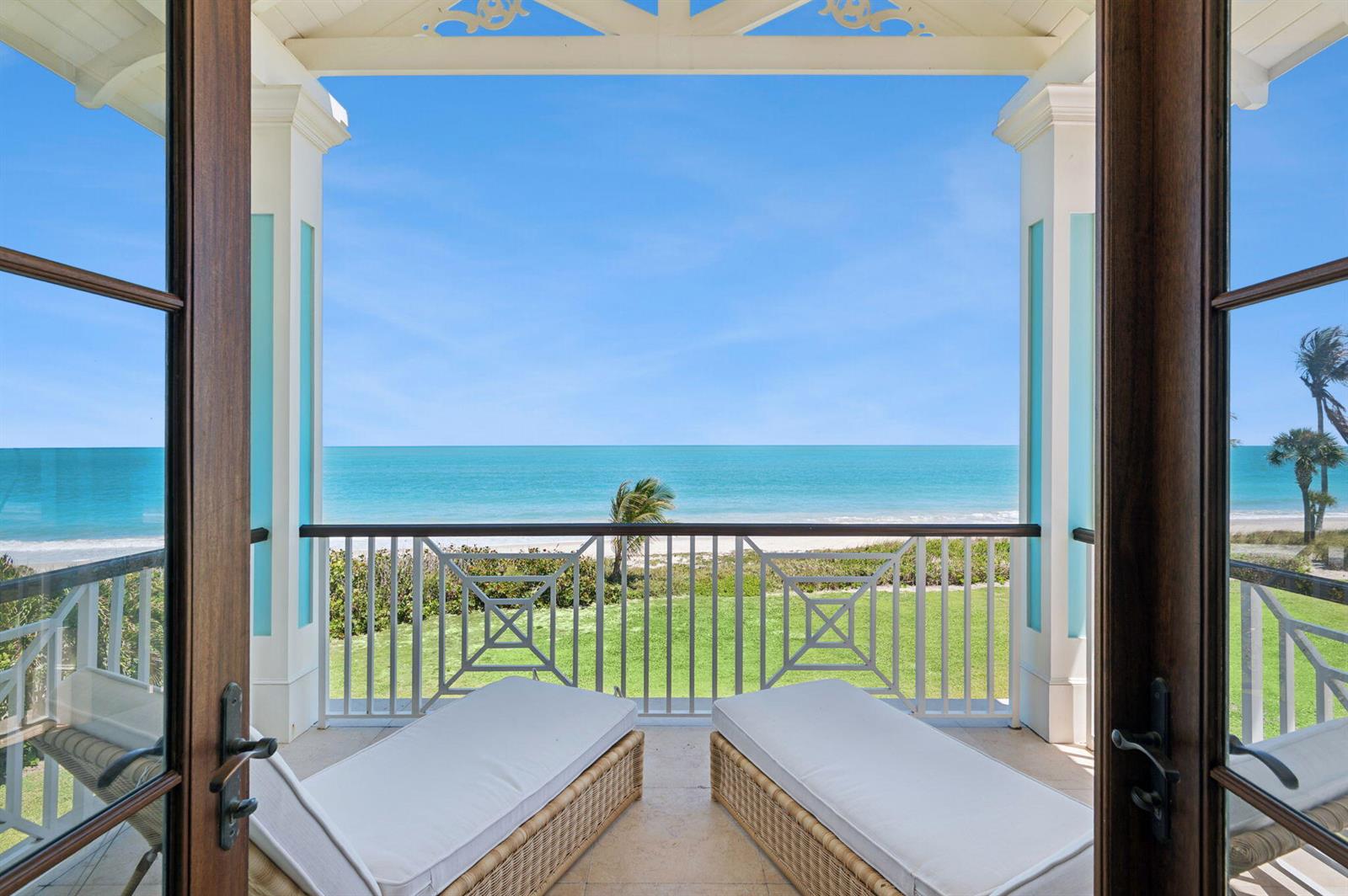 A balcony with two lounge chairs overlooks a grassy lawn and the ocean — 716 Reef Road, Vero Beach FL 32963, VERO BEACH, FL