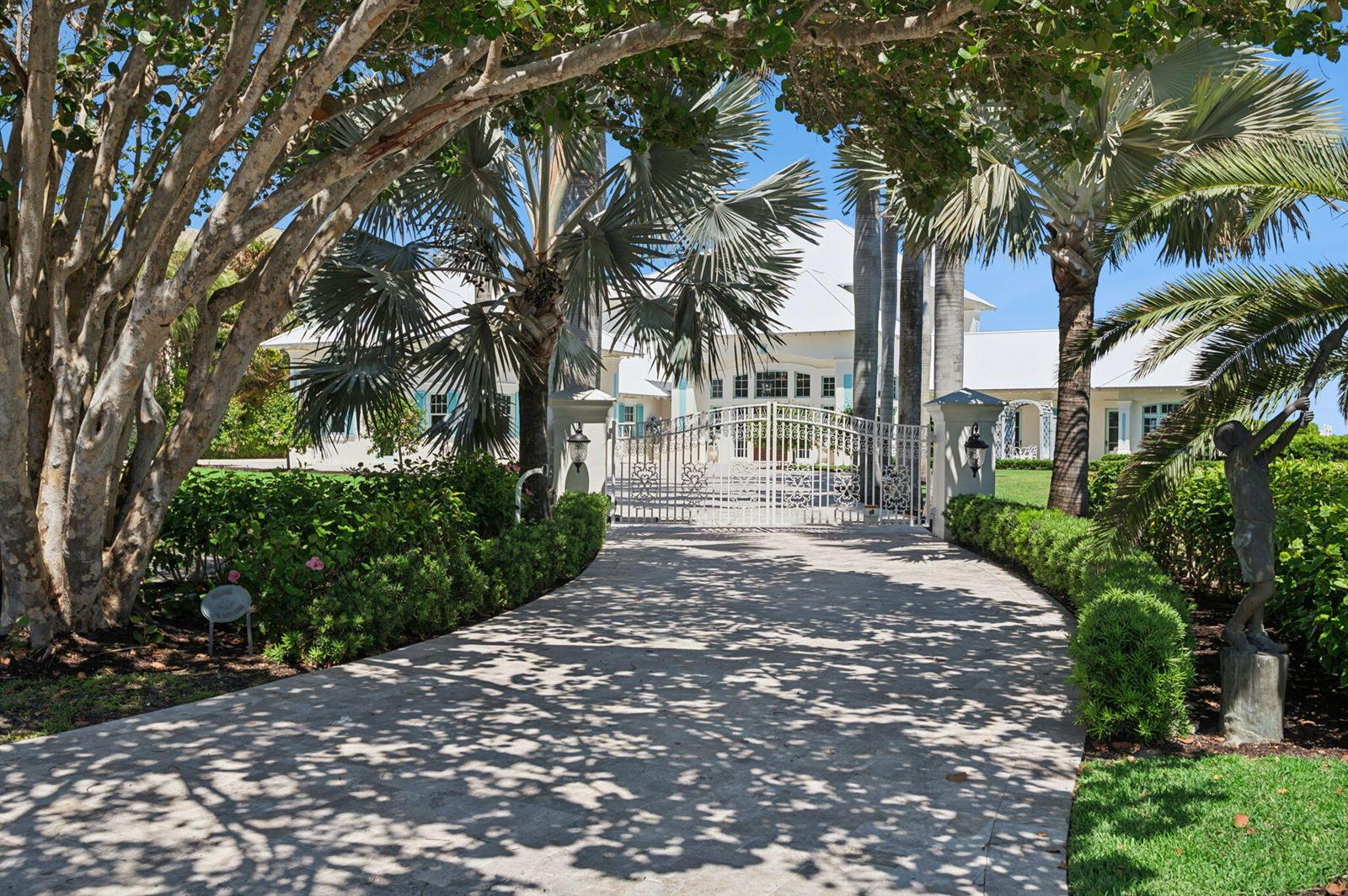 A paved driveway leads through a gated entrance to a white house with palm trees — 716 Reef Road, Vero Beach FL 32963, VERO BEACH, FL