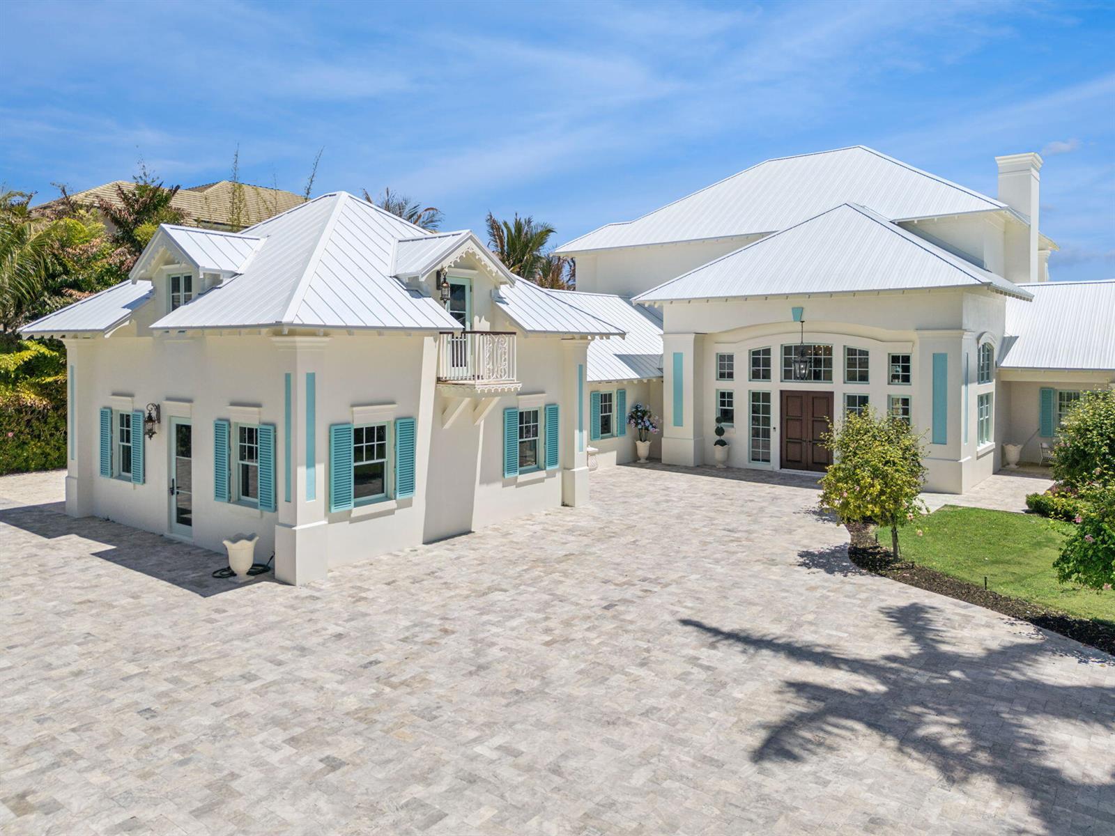 A large white house with a metal roof, blue shutters, and a stone-paved driveway — 716 Reef Road, Vero Beach FL 32963, VERO BEACH, FL