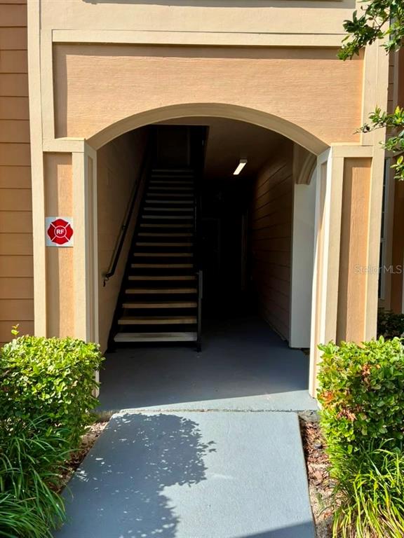 An arched entryway leads to an outdoor staircase between two tan building walls — 1995 ERVING CIRCLE UNIT 307, OCOEE, FL