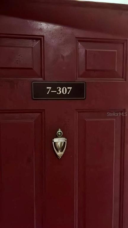 A dark red door features a silver door knocker and a sign reading 7-307 — 1995 ERVING CIRCLE UNIT 307, OCOEE, FL