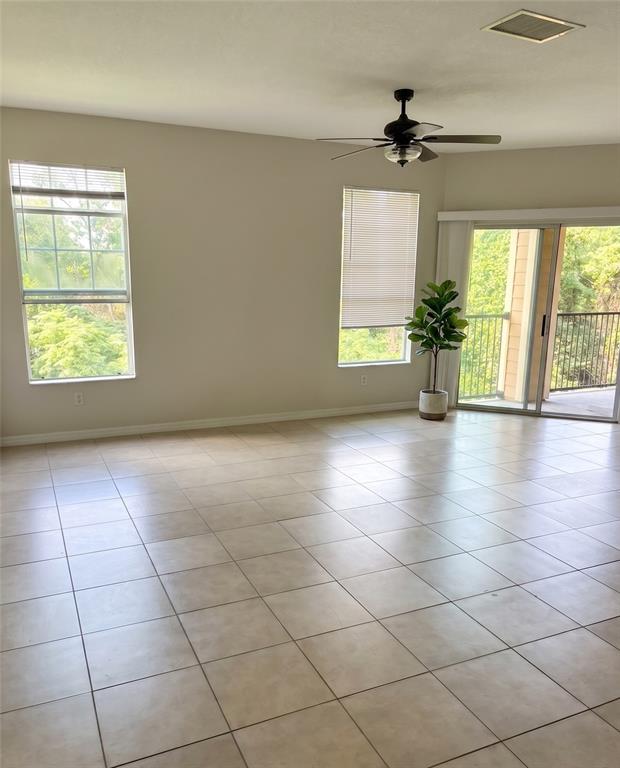 An empty living room features tile flooring, a ceiling fan, and a sliding glass door — 1995 ERVING CIRCLE UNIT 307, OCOEE, FL