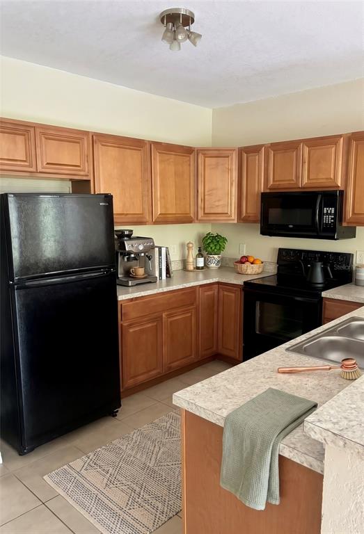 A kitchen features wood cabinets, black appliances, and light-colored countertops — 1995 ERVING CIRCLE UNIT 307, OCOEE, FL