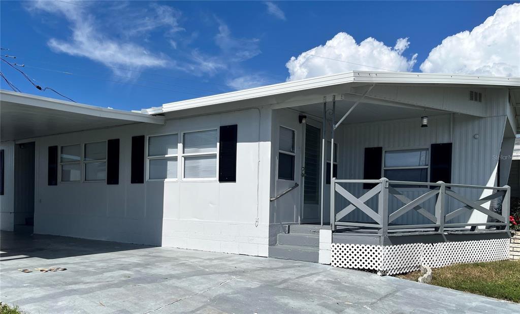 A white mobile home with a carport, a front porch, and a concrete driveway — 207 51ST AVENUE PLAZA W UNIT 3, BRADENTON, FL