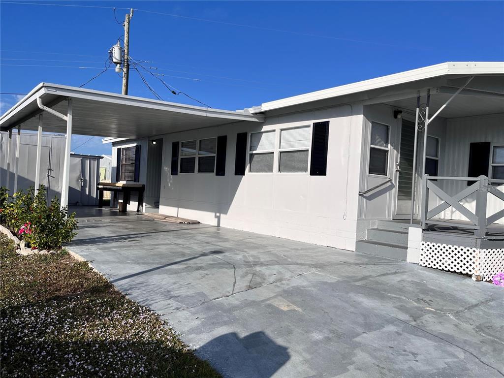 The exterior of a mobile home features a carport, a small front porch, and siding — 207 51ST AVENUE PLAZA W UNIT 3, BRADENTON, FL