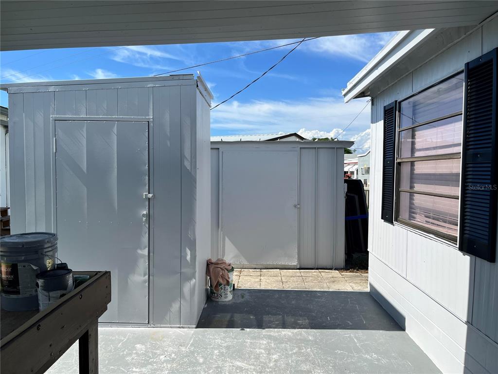 A concrete patio area features two metal storage sheds and the side of a house — 207 51ST AVENUE PLAZA W UNIT 3, BRADENTON, FL