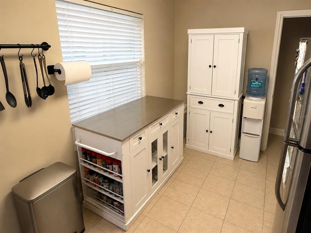 A kitchen area features a white cabinet island with a stainless steel countertop and shelving — 3142 HENDERSON CIRCLE W, LAKELAND, FL
