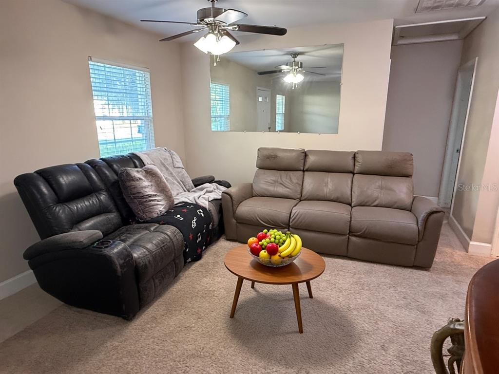 A living room features two leather sofas, a round coffee table, and a wall mirror — 3142 HENDERSON CIRCLE W, LAKELAND, FL