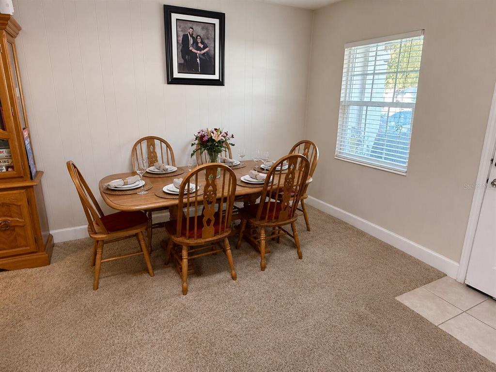A dining room features a wooden table with six chairs, carpeted flooring, and a window — 3142 HENDERSON CIRCLE W, LAKELAND, FL