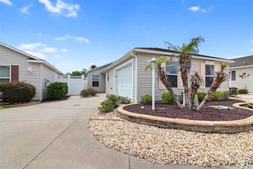 A beige single-story house features a concrete driveway, a garage, and a landscaped front yard — 2264 WAYLAND STREET, THE VILLAGES, FL