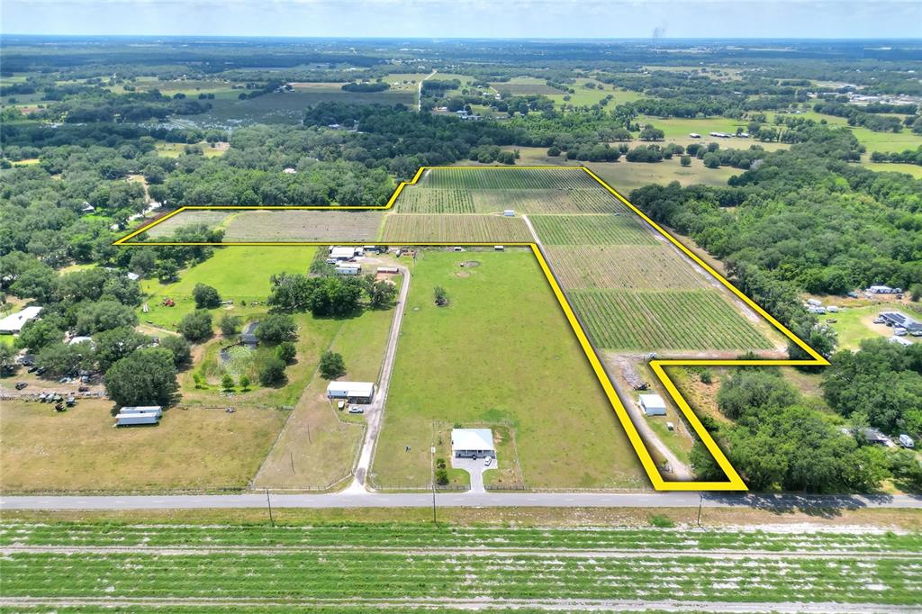 An aerial view shows a rural property with a house, outbuildings, and agricultural fields — 3674 E STATE ROAD 64, ZOLFO SPRINGS, FL
