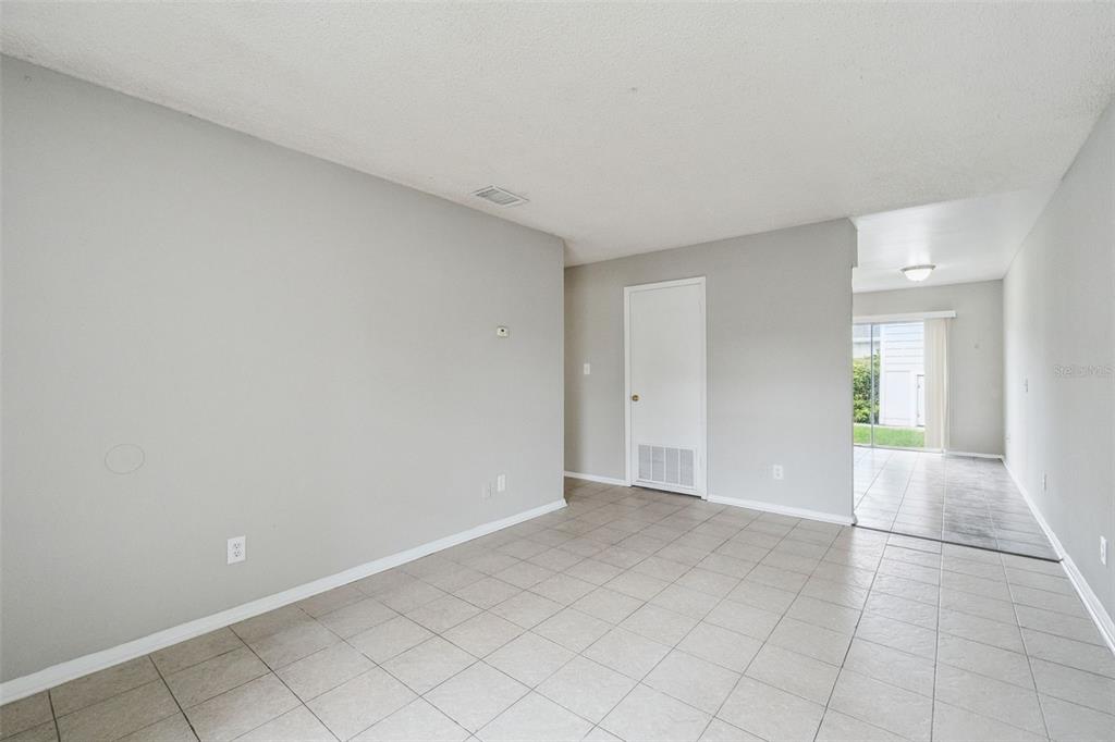 An empty room with light gray walls, tiled floors, and a white interior door — 2 LAKE VILLA WAY, KISSIMMEE, FL