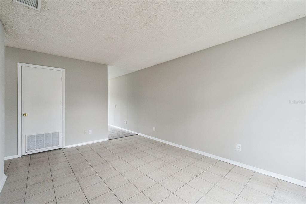 A room with light gray walls, white trim, and light-colored tile flooring — 2 LAKE VILLA WAY, KISSIMMEE, FL