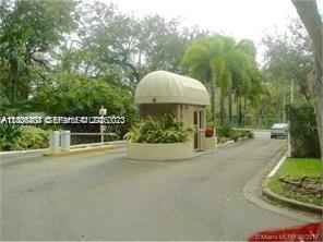 A gated community entrance features a small guardhouse with a curved roof and lush landscaping — 780 NE 69th St # 1406, Miami FL 33138, MIAMI, FL