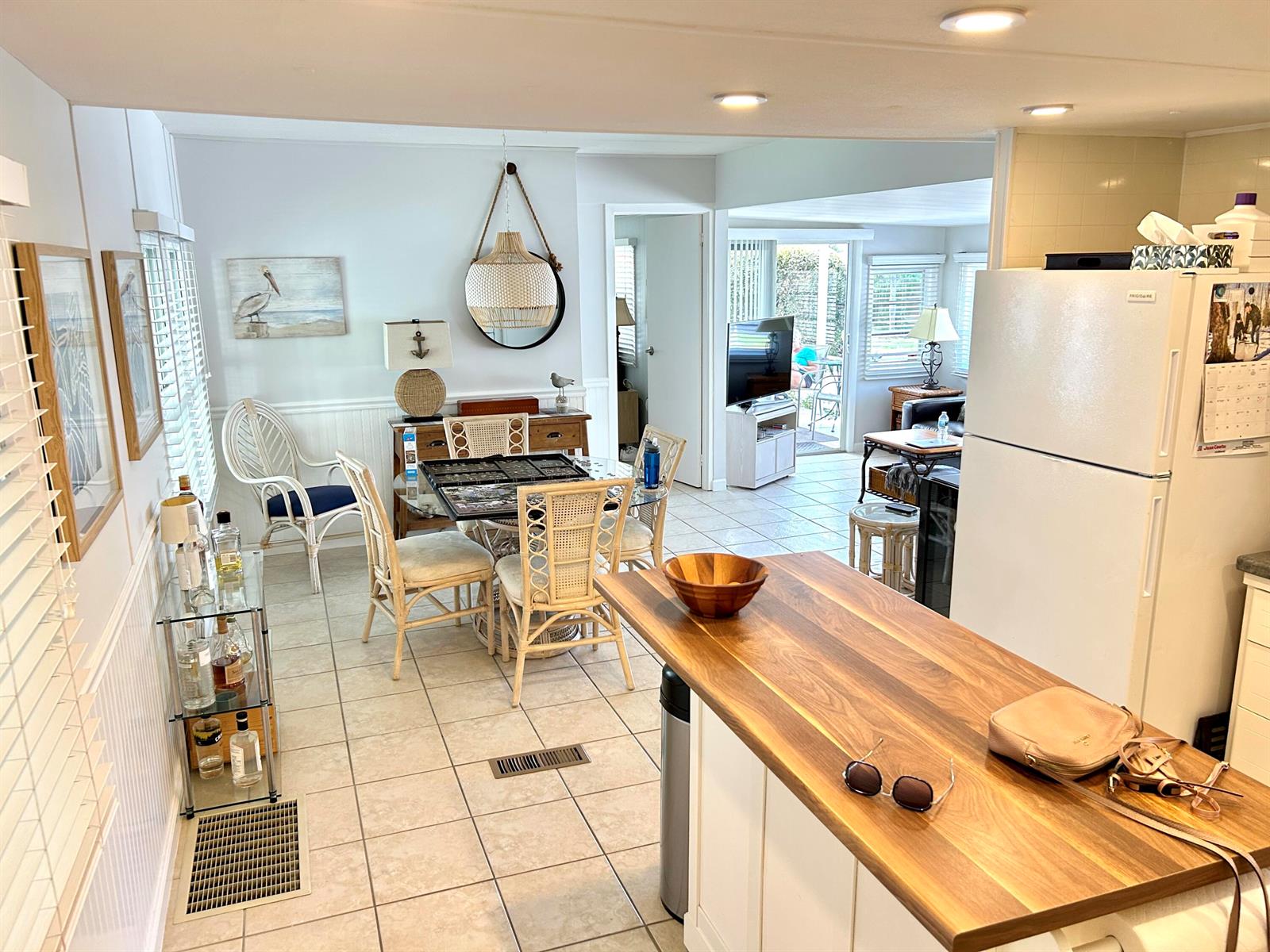 A kitchen with a wood countertop overlooks a dining area featuring wicker chairs and tile floors — 312 Hibiscus Drive, Deerfield Beach FL 33442, DEERFIELD BEACH, FL