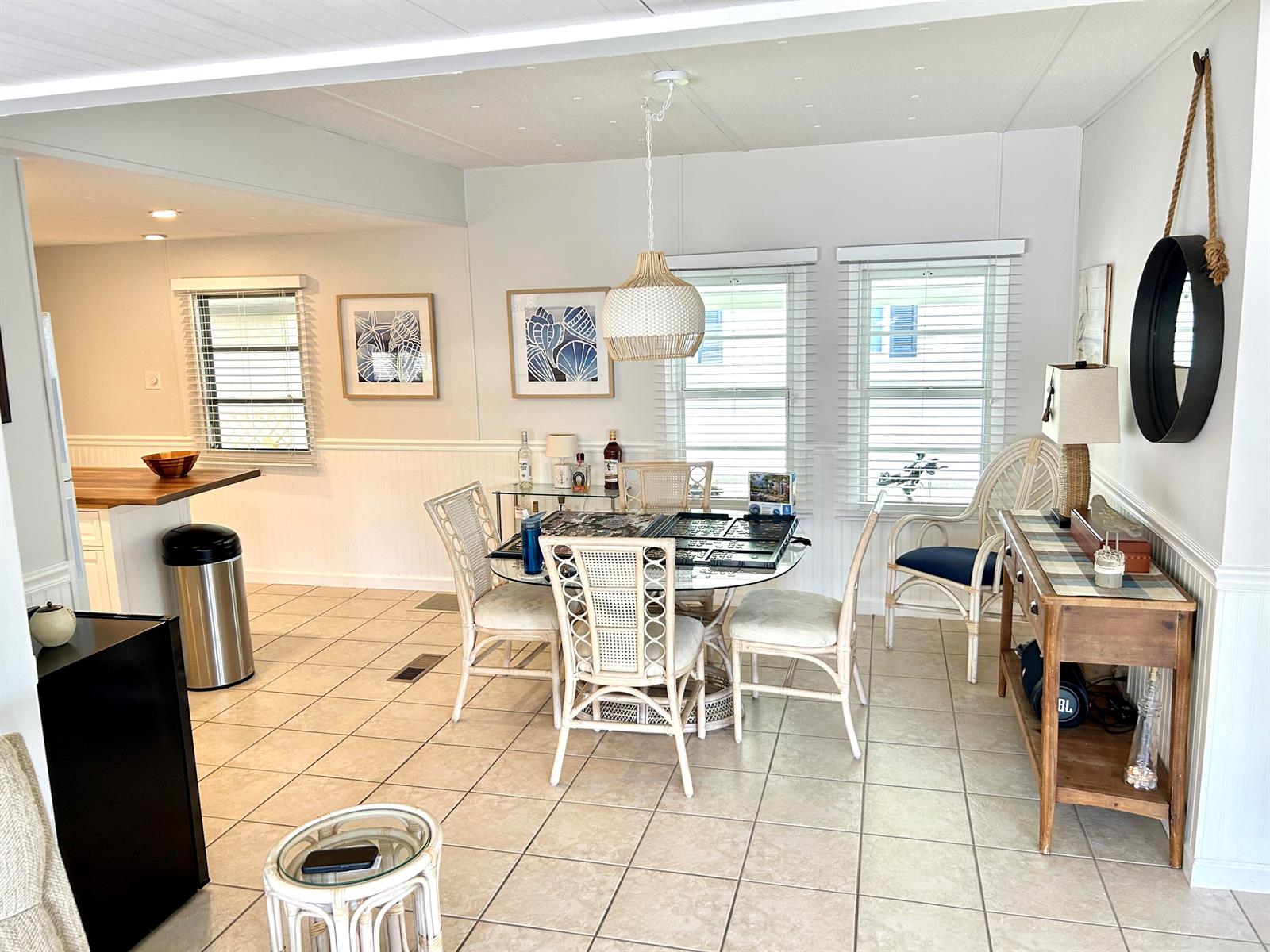 A dining area features a glass-topped table, wicker chairs, tile flooring, and a hanging pendant light — 312 Hibiscus Drive, Deerfield Beach FL 33442, DEERFIELD BEACH, FL