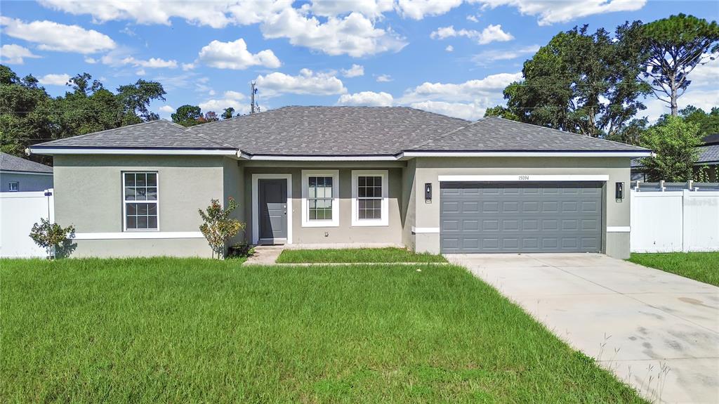 A single-story house with a gray exterior, a two-car garage, and a front lawn — 15094 SW 43RD AVENUE ROAD, OCALA, FL
