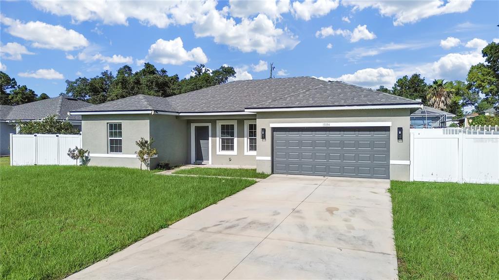 A single-story house with a gray garage door, white trim, and a concrete driveway — 15094 SW 43RD AVENUE ROAD, OCALA, FL