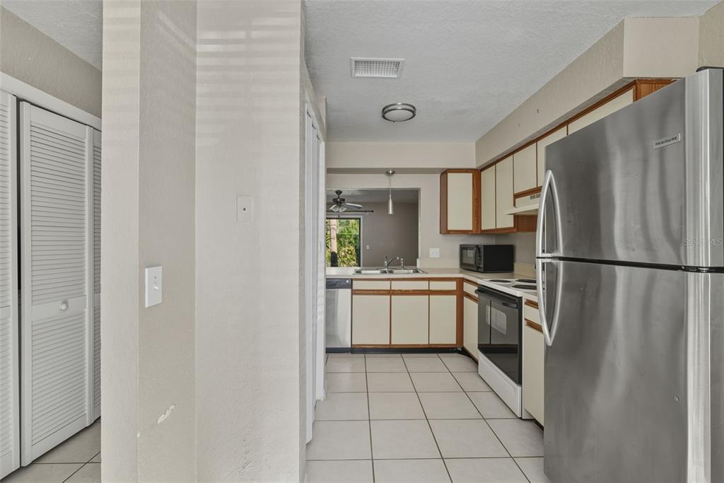 A kitchen features white cabinets, stainless steel appliances, and light-colored tile flooring — 16545 LAKE BRIGADOON CIRCLE, TAMPA, FL