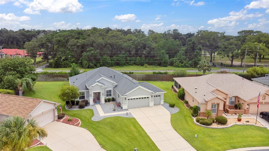 An aerial view shows a suburban house with a gray roof, garage, and landscaped lawn — 13944 SE 96TH CIRCLE, SUMMERFIELD, FL