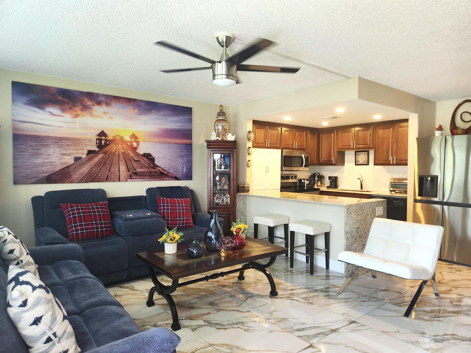 A living room with blue sofas, a coffee table, and an open kitchen with granite counters — 1012 Ellesmere A # 1012, Deerfield Beach FL 33442, DEERFIELD BEACH, FL