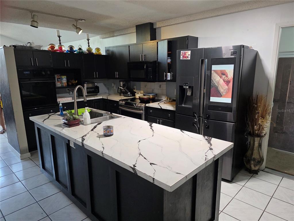 A kitchen features dark cabinets, a white marble-patterned island countertop, and stainless steel appliances — 142 NE 112TH AVENUE, OLD TOWN, FL