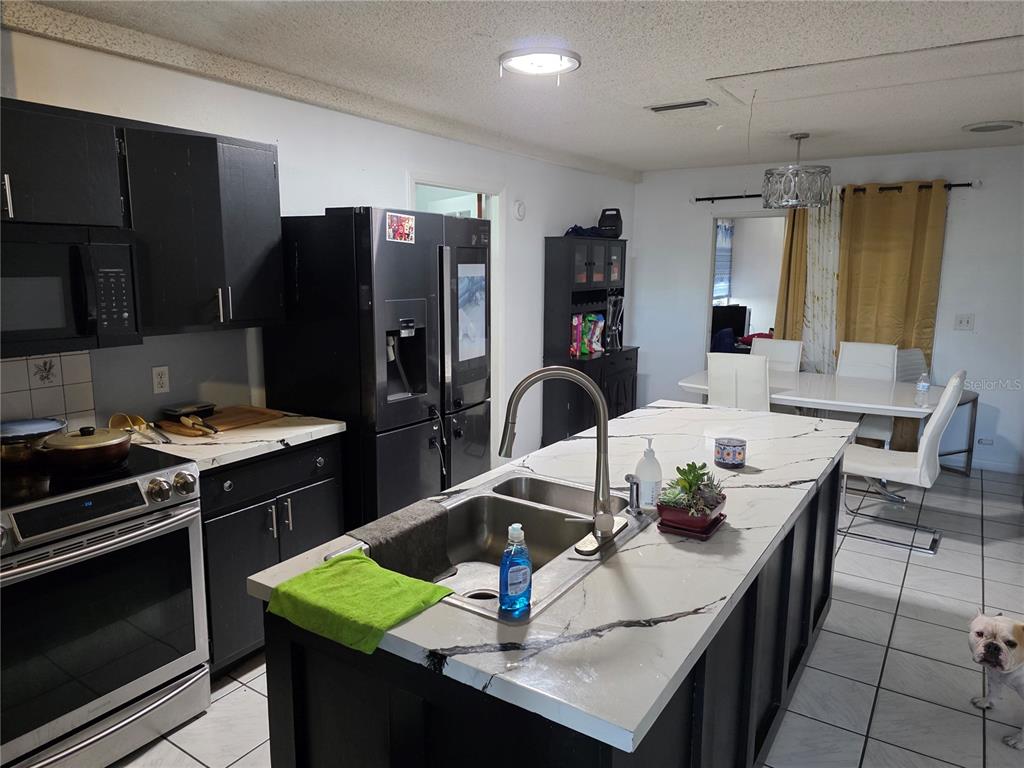 A kitchen features black cabinetry, a white marble-patterned island with a sink, and tile flooring — 142 NE 112TH AVENUE, OLD TOWN, FL