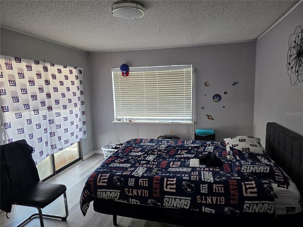 A bedroom features New York Giants themed bedding and window treatments with light gray walls — 142 NE 112TH AVENUE, OLD TOWN, FL
