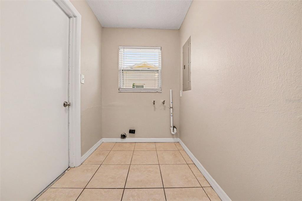 A laundry room with beige tile flooring, a window, and plumbing hookups on the wall — 1895 S IVEY LANE, ORLANDO, FL