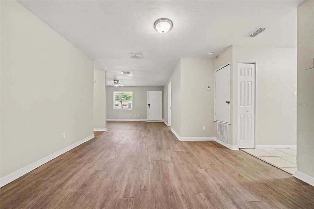 An interior view shows a living area with wood-look flooring, white walls, and a closet — 1895 S IVEY LANE, ORLANDO, FL