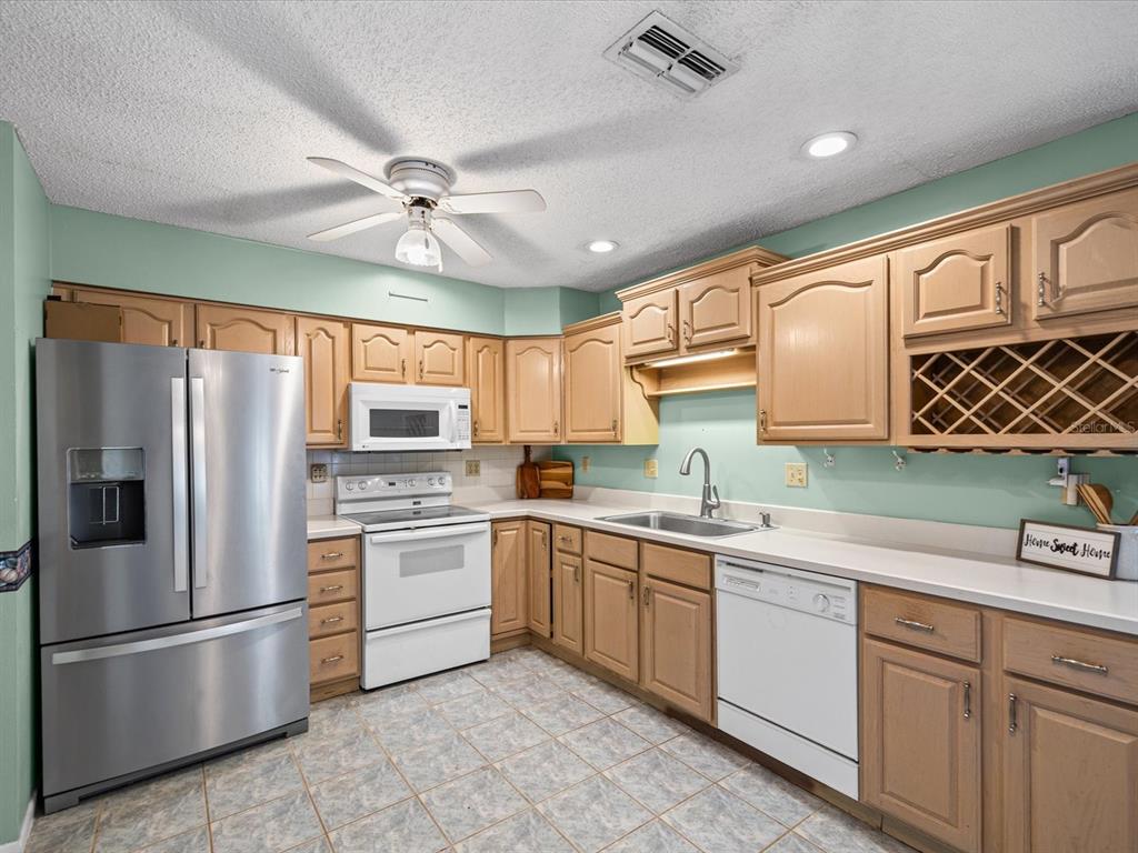 A kitchen with light wood cabinets, white appliances, a stainless steel refrigerator, and mint walls — 4135 COTTON TAIL DRIVE, NEW PORT RICHEY, FL