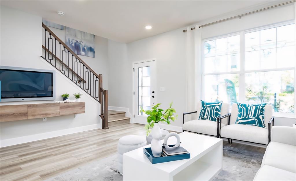 A living room features a floating wooden console, a staircase with iron railings, and armchairs — 15212 TRIBUTE OVATION WAY, WINTER GARDEN, FL
